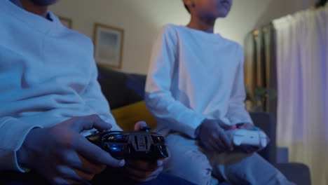 Close-Up-On-Hands-Of-Two-Young-Boys-At-Home-Playing-With-Computer-Games-Console-On-TV-Holding-Controllers-Late-At-Night-7